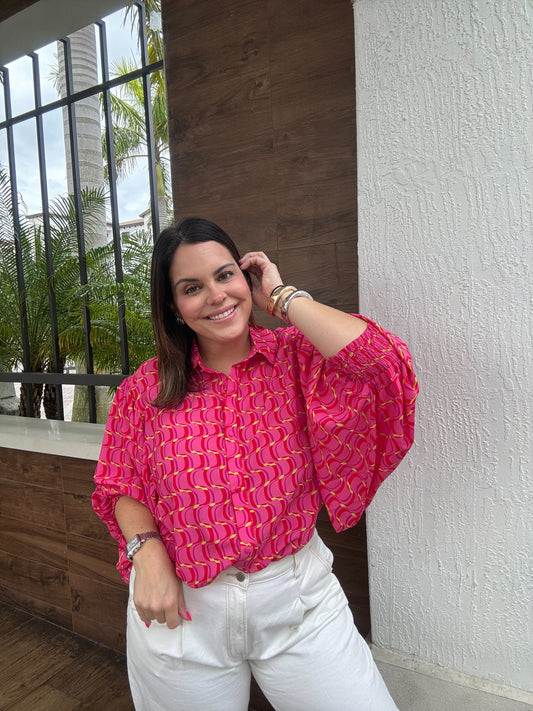 A women's pink printed blouse top featuring a button down front.